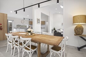Eine moderne Küche mit weißen Schränken, einem Holztisch und weißen Stühlen.