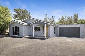 Ett modernt enplanshus med garage, en inglasad veranda och en uppfart.