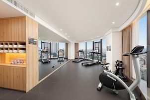 Ein modernes Fitnessstudio mit Laufbändern, einem Biocor Ellipsentrainer und einer Trinkstation.