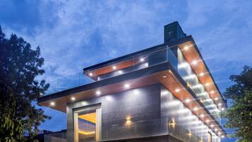 A modern multi-story building with a flat roof, large windows, and a well-lit exterior.