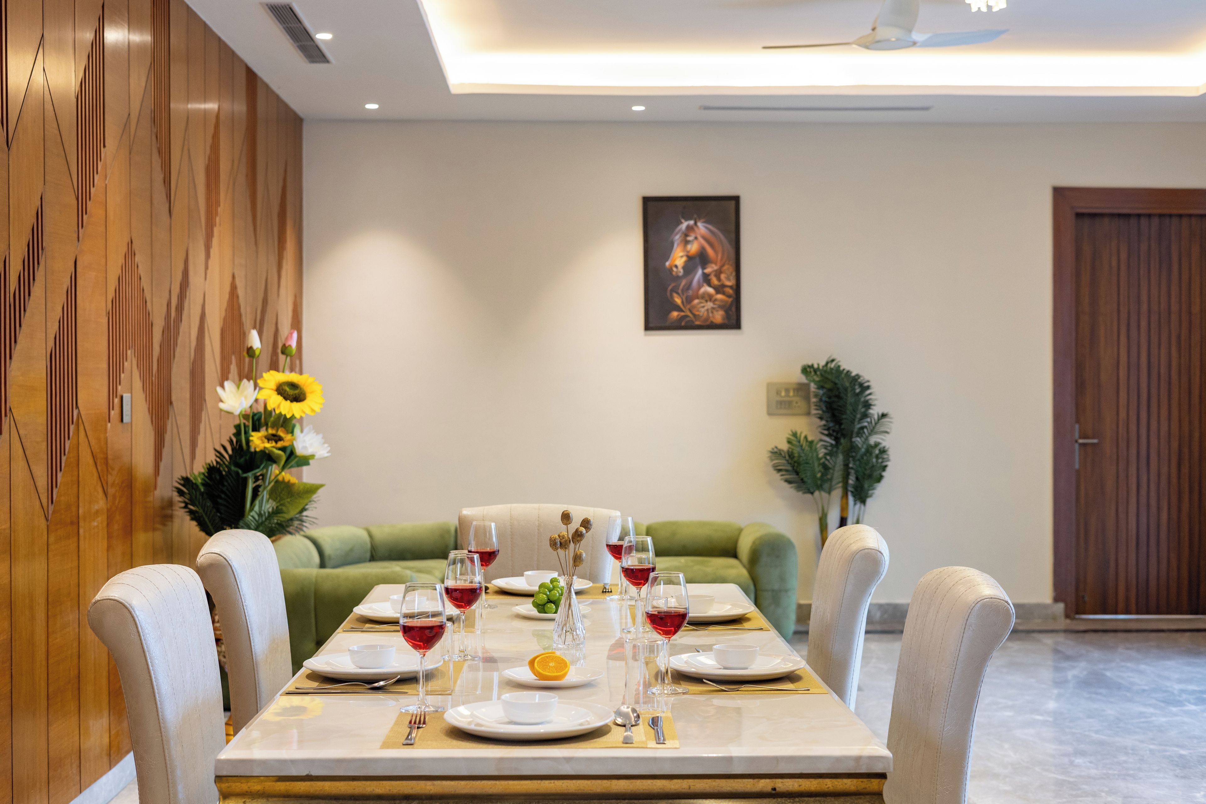 A dining area with a long table set for a meal, a sofa, and a door in the background.
