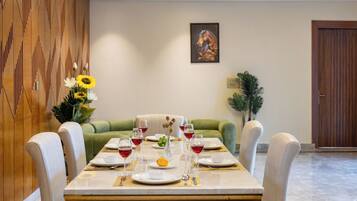 A dining area with a long table set for a meal, a sofa, and a door in the background.
