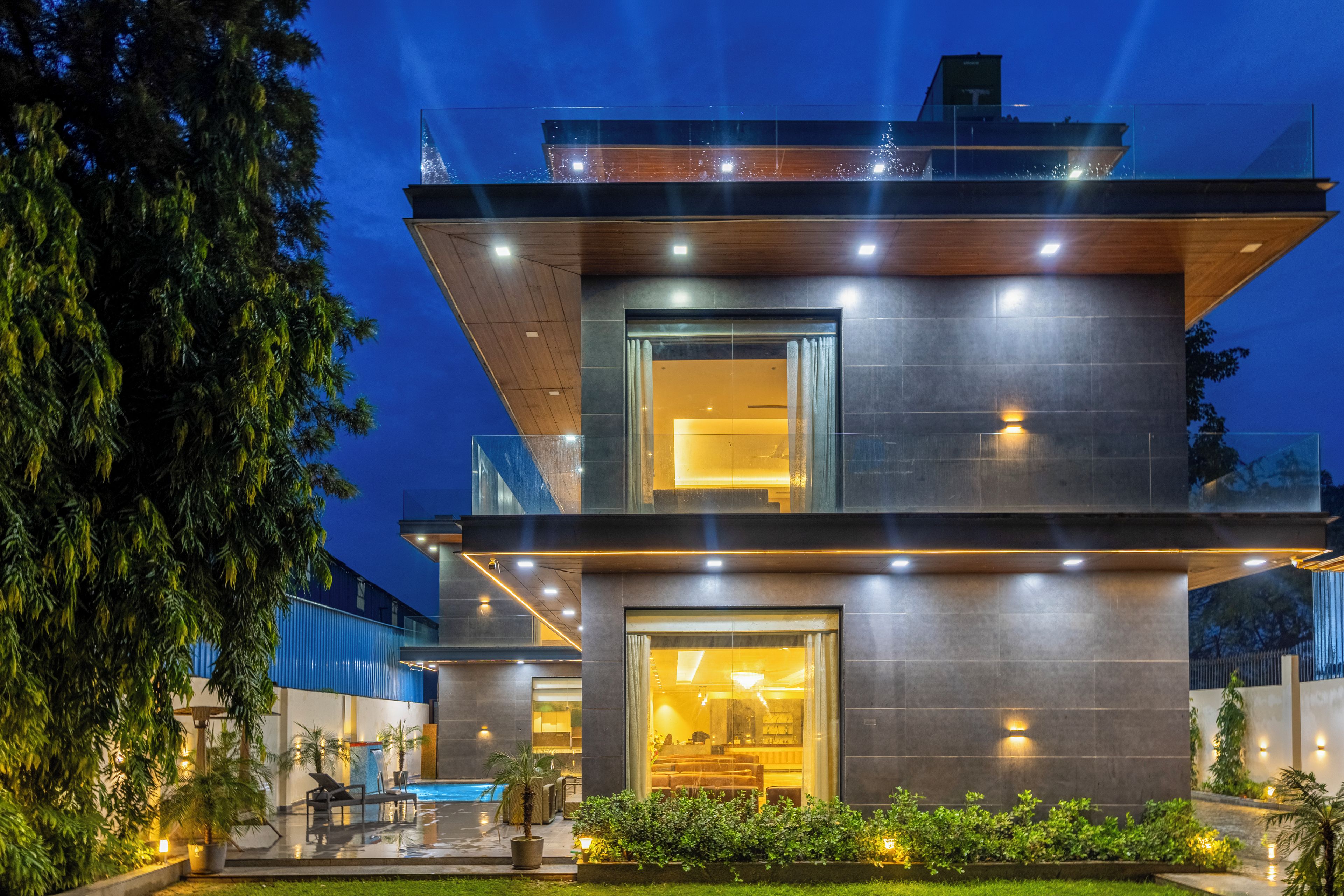 Un edificio moderno con fachada de vidrio, mesas al aire libre y una piscina.