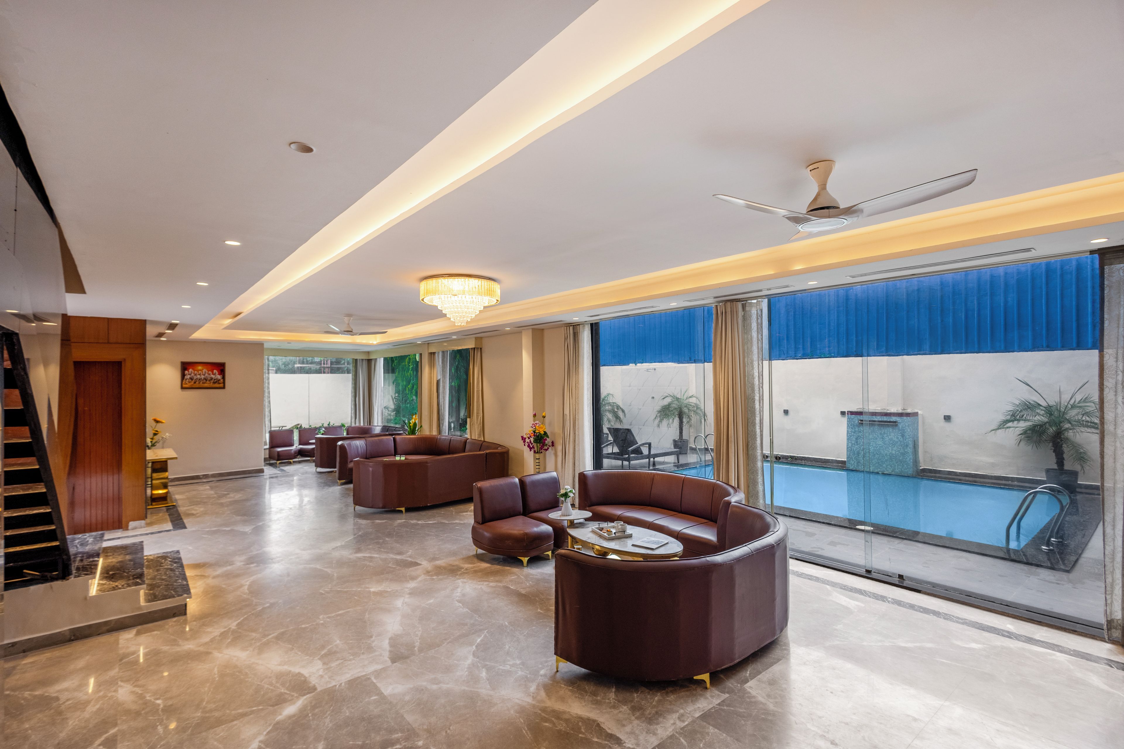 Eine Hotelhalle mit Blick auf einen Pool, Ledersofas und einem Kronleuchter.