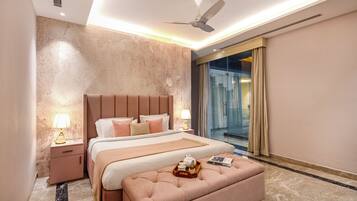 A modern bedroom with a large bed, a ceiling fan, a glass shower, and a marble floor.