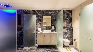 Un baño moderno con suelo de mármol, cabina de ducha de cristal y lavabo empotrado con espejo.