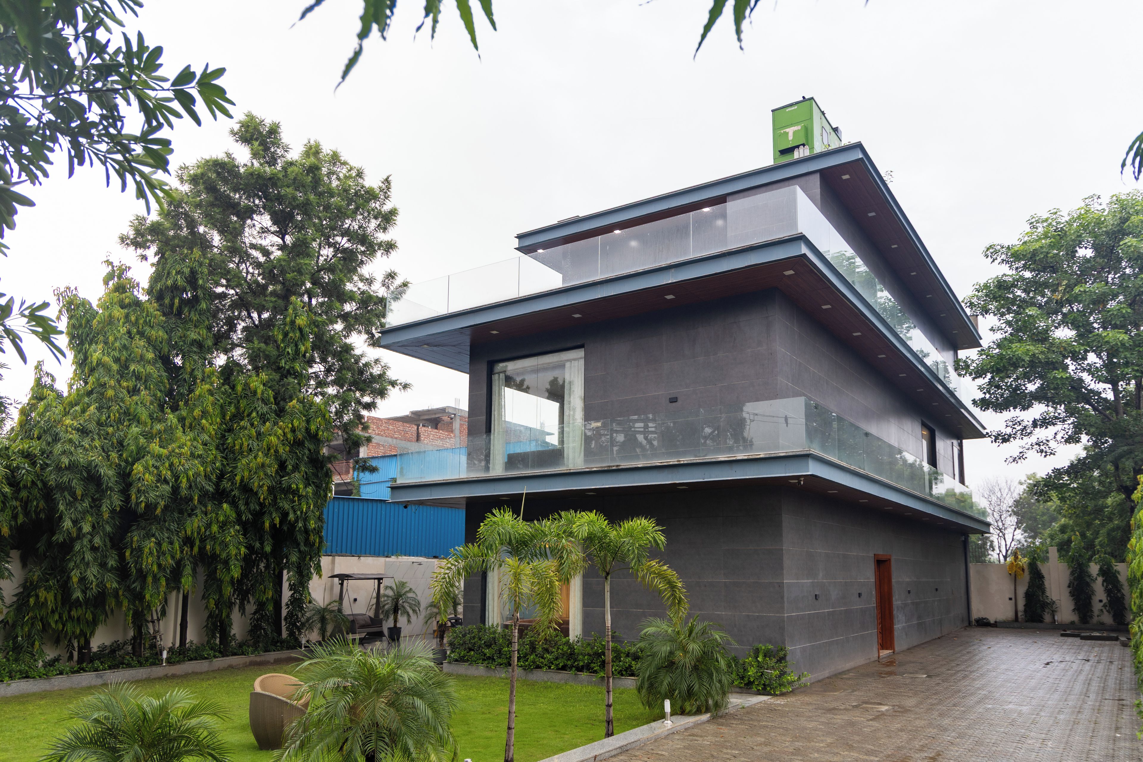 A modern two-story building with a flat roof, large windows, and a balcony.