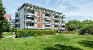 A multi-story residential building with balconies, a flat roof, and a garden area in front. - Apartments Nikolina - Comfort Two Bedroom Apartment (Split)