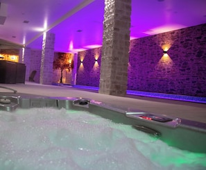 Uma área de spa com hidromassagem, paredes de pedra e iluminação suave.