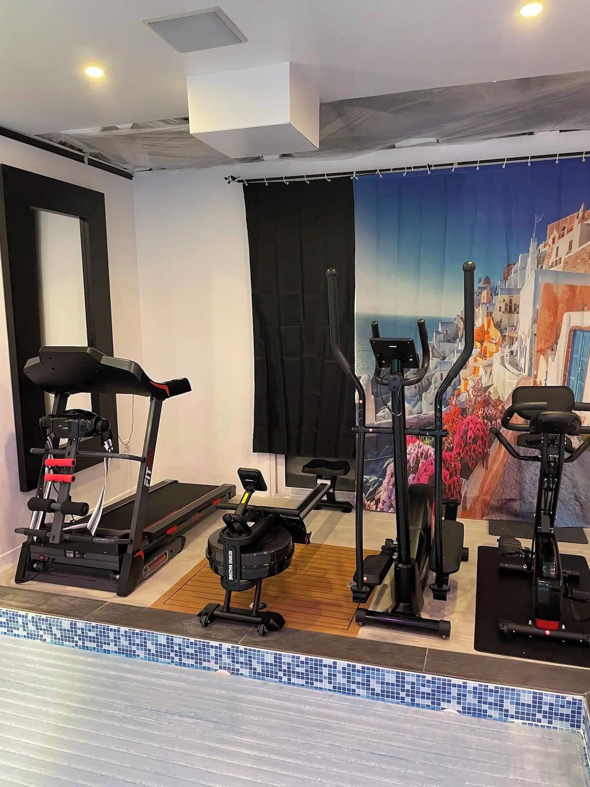 A gym with treadmills, a stationary bike, and a rowing machine.