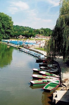 Un río tranquilo con barcas amarradas a la orilla, rodeado de exuberante vegetación y un cielo despejado.