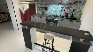 Una cocina moderna con una isla central, taburetes de bar e iluminación colgante.