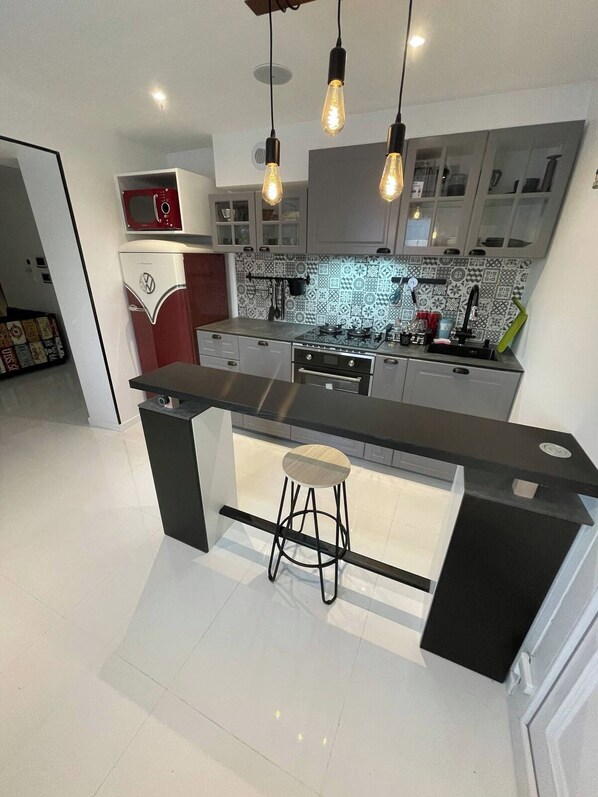 Una cocina moderna con una isla central, taburetes de bar e iluminación colgante.
