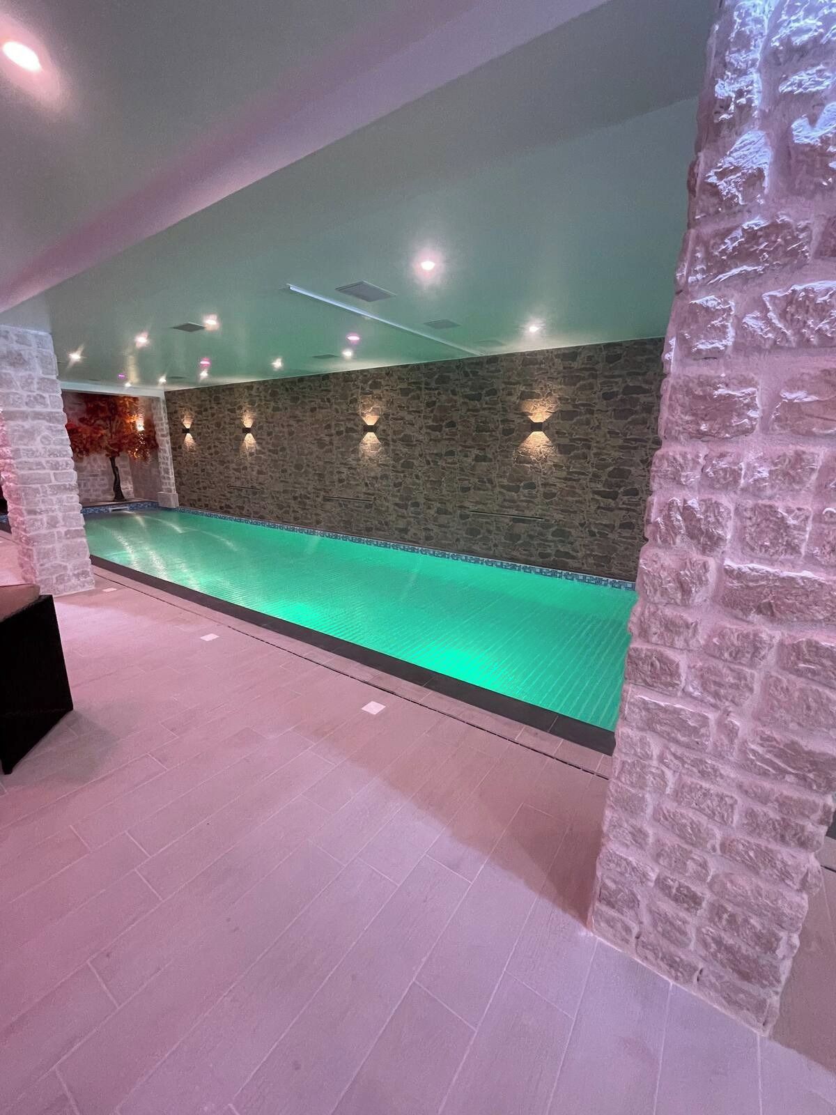 Una piscina con muro de piedra e iluminación empotrada.