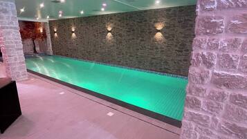 Una piscina con muro de piedra e iluminación empotrada.
