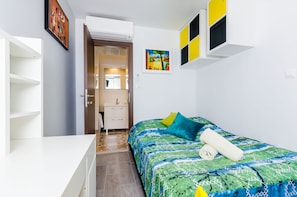 Ein Schlafzimmer mit einem Bett, einem weißen Kleiderschrank, einem Badezimmer mit einem Waschbecken und einer Tür zu einem anderen Raum.