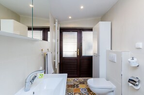 Ein Badezimmer mit einem weißen Waschbecken, einer Toilette und einer Duschkabine.