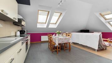 A modern kitchen with a dining area, featuring a table set for two, a radiator, and skylights.