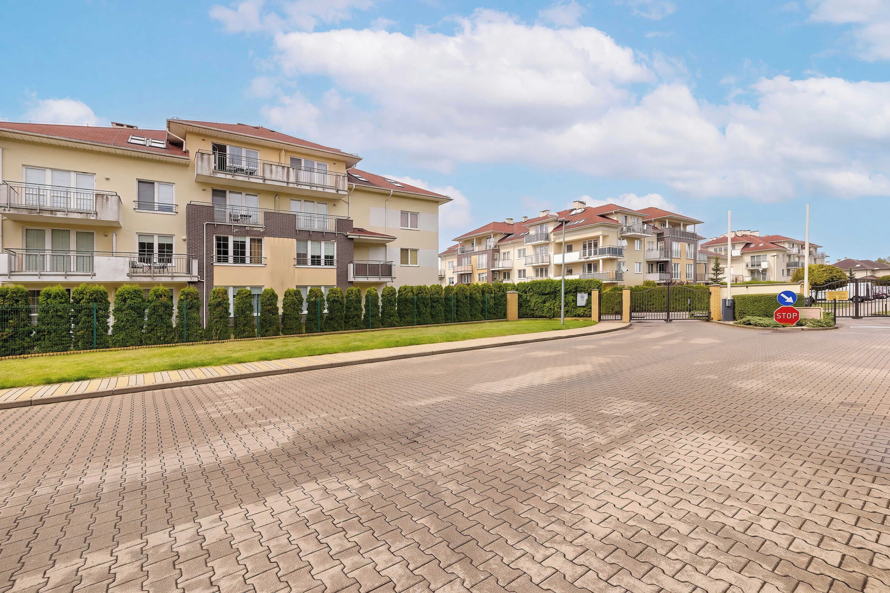 A residential building with multiple balconies, a paved driveway, and a stop sign.