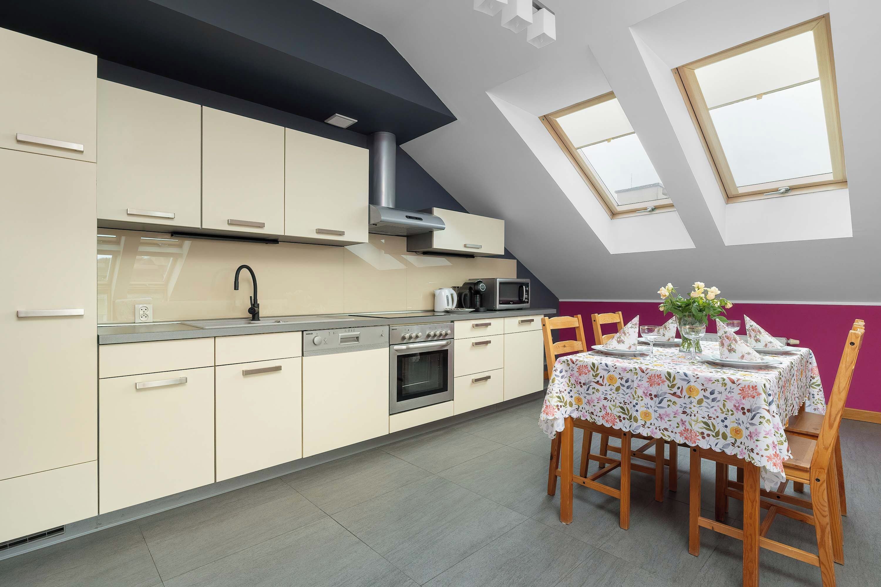 A modern kitchen with a dining area, featuring a built-in oven, microwave, and a large window.