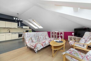 Eine moderne Loft-Wohnung mit Küche, einer Couch, einem Couchtisch und einem Fernseher.
