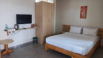 A hotel room with a bed, a TV, a small table, and a wardrobe.