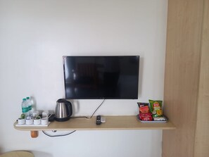 Un televisor de pantalla plana sujeto a una pared sobre un estante de madera.