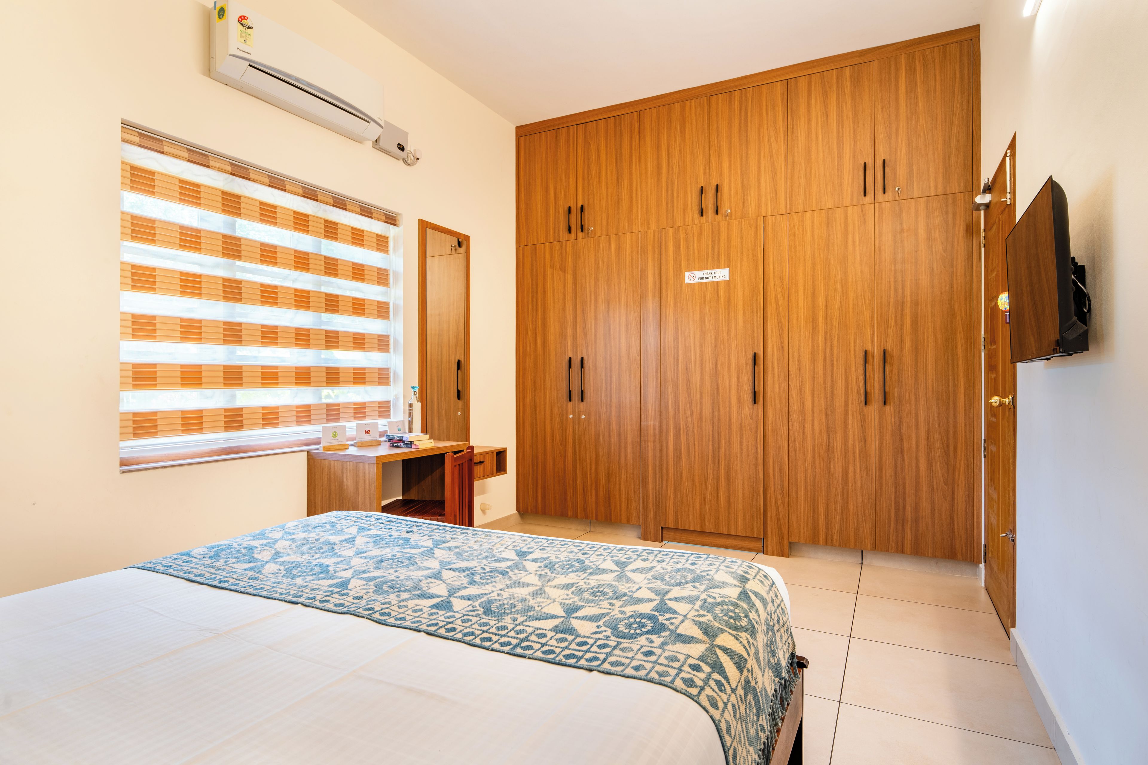A bedroom with a bed, a wardrobe, a desk, and a television.