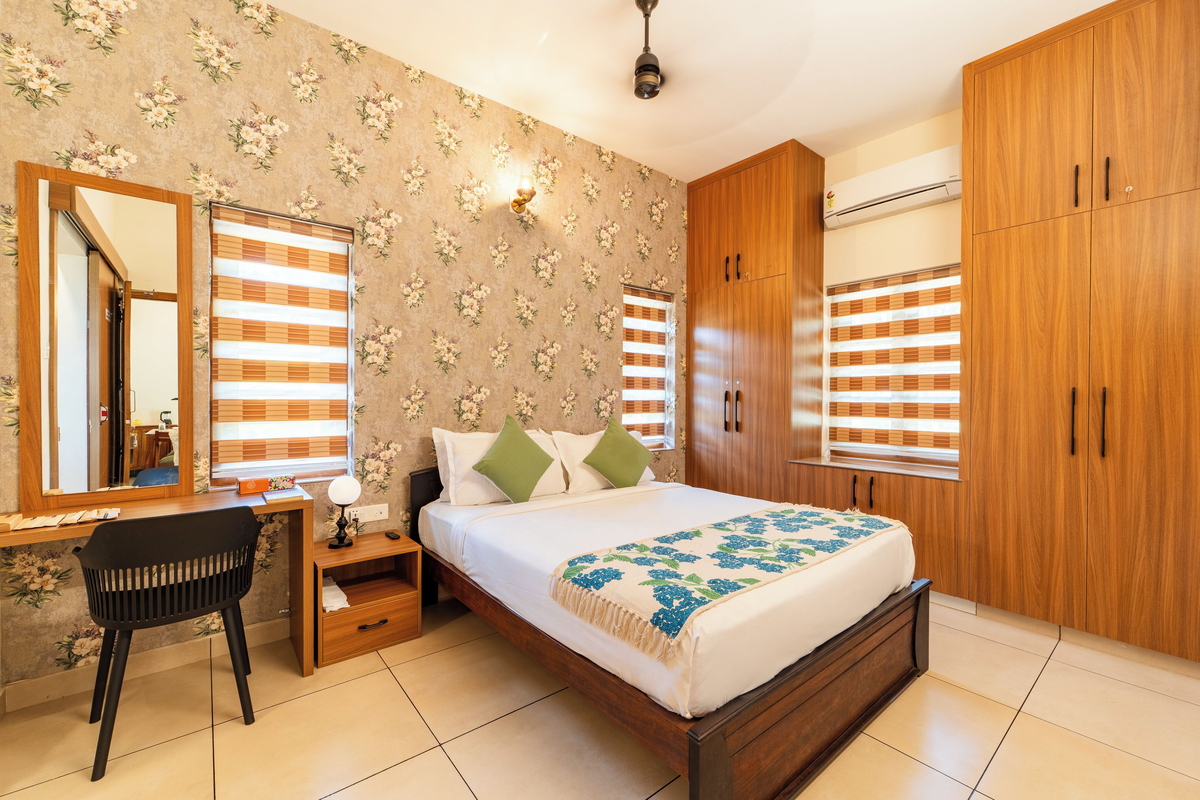 Ein Schlafzimmer mit Bett, Schreibtisch, Stuhl, Kleiderschrank und Spiegel.