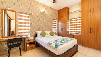 A bedroom with a bed, a desk, a chair, a wardrobe, and a mirror.