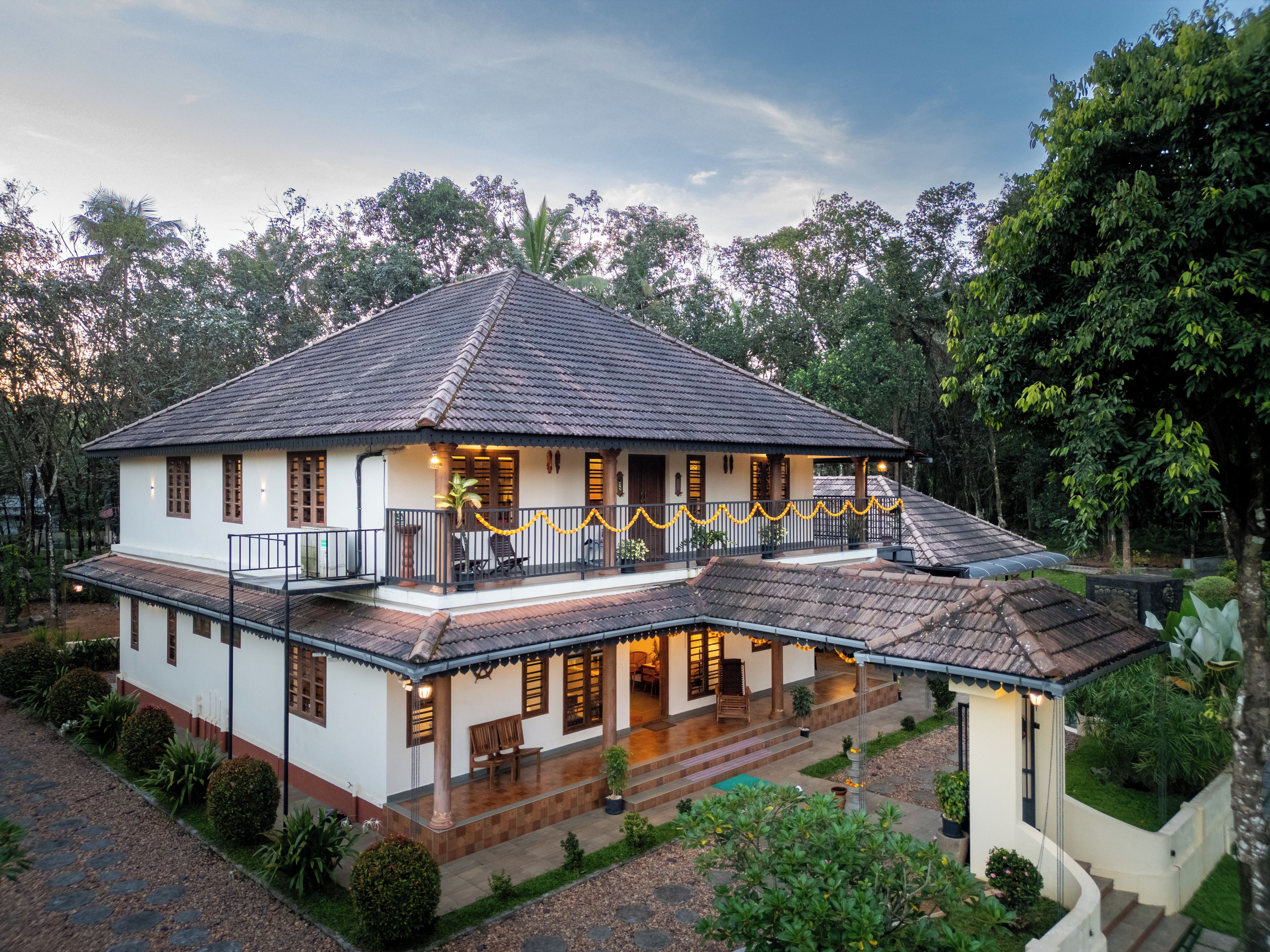 A two-story house with a balcony, surrounded by greenery.