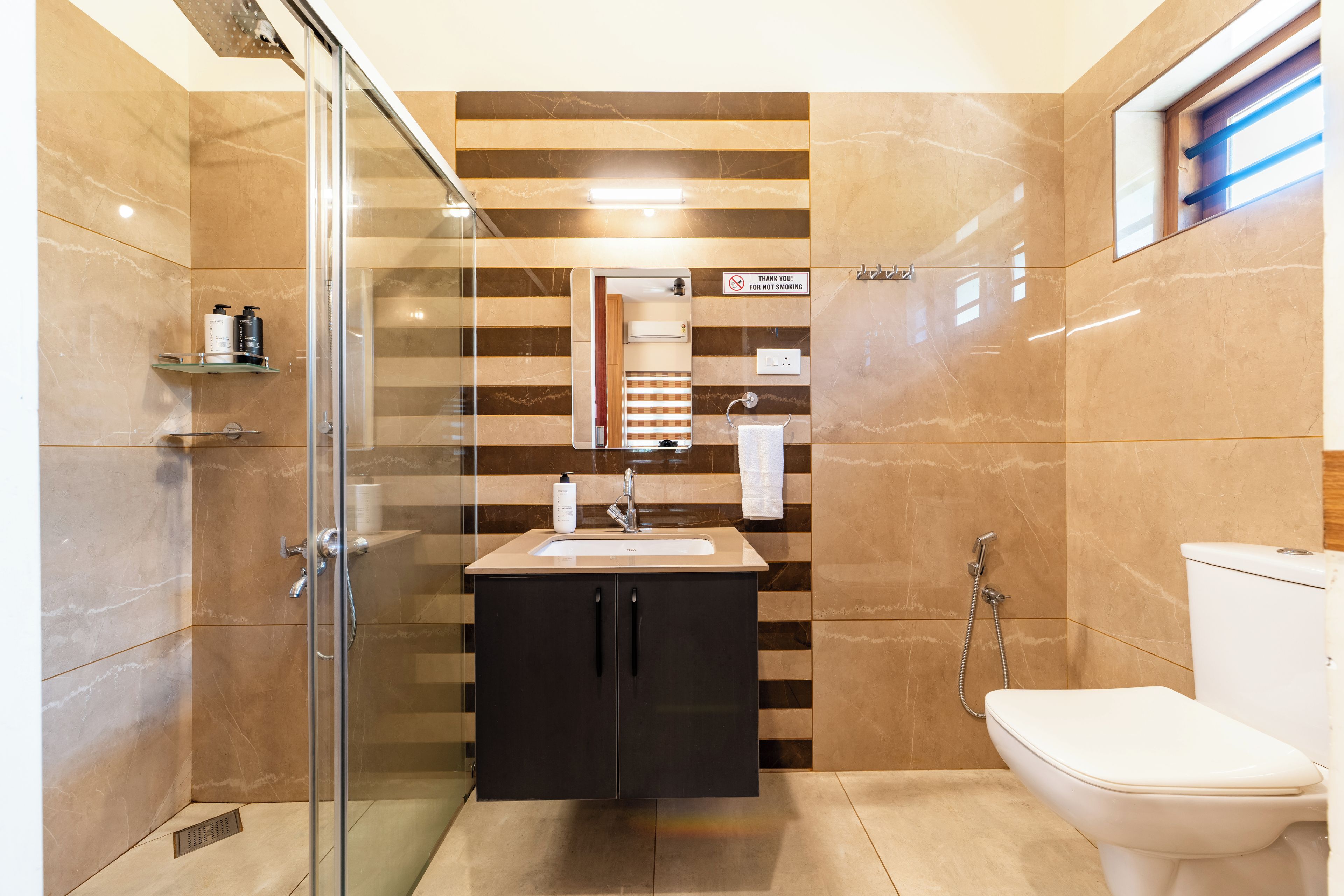 Un baño moderno con cabina de ducha de vidrio, tocador con lavamanos y un inodoro.