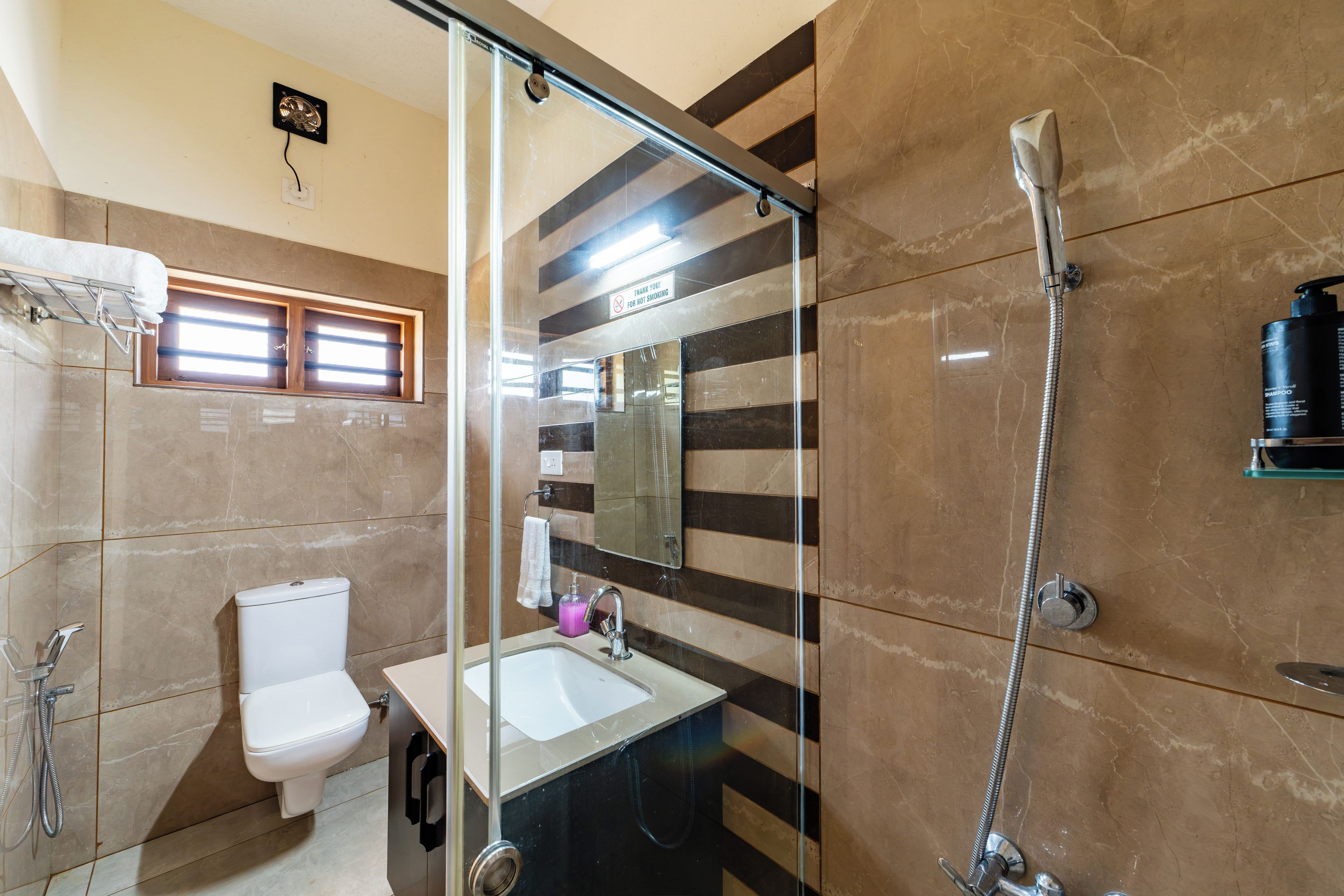 Un baño con cabina de ducha de vidrio, inodoro, lavabo y espejo.