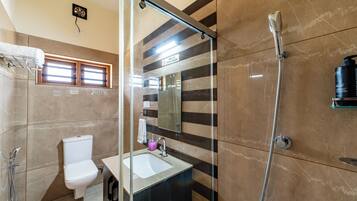 Un baño con cabina de ducha de vidrio, inodoro, lavabo y espejo.