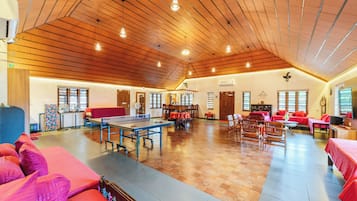 A spacious indoor area with a ping pong table, seating arrangements, and a high wooden ceiling.