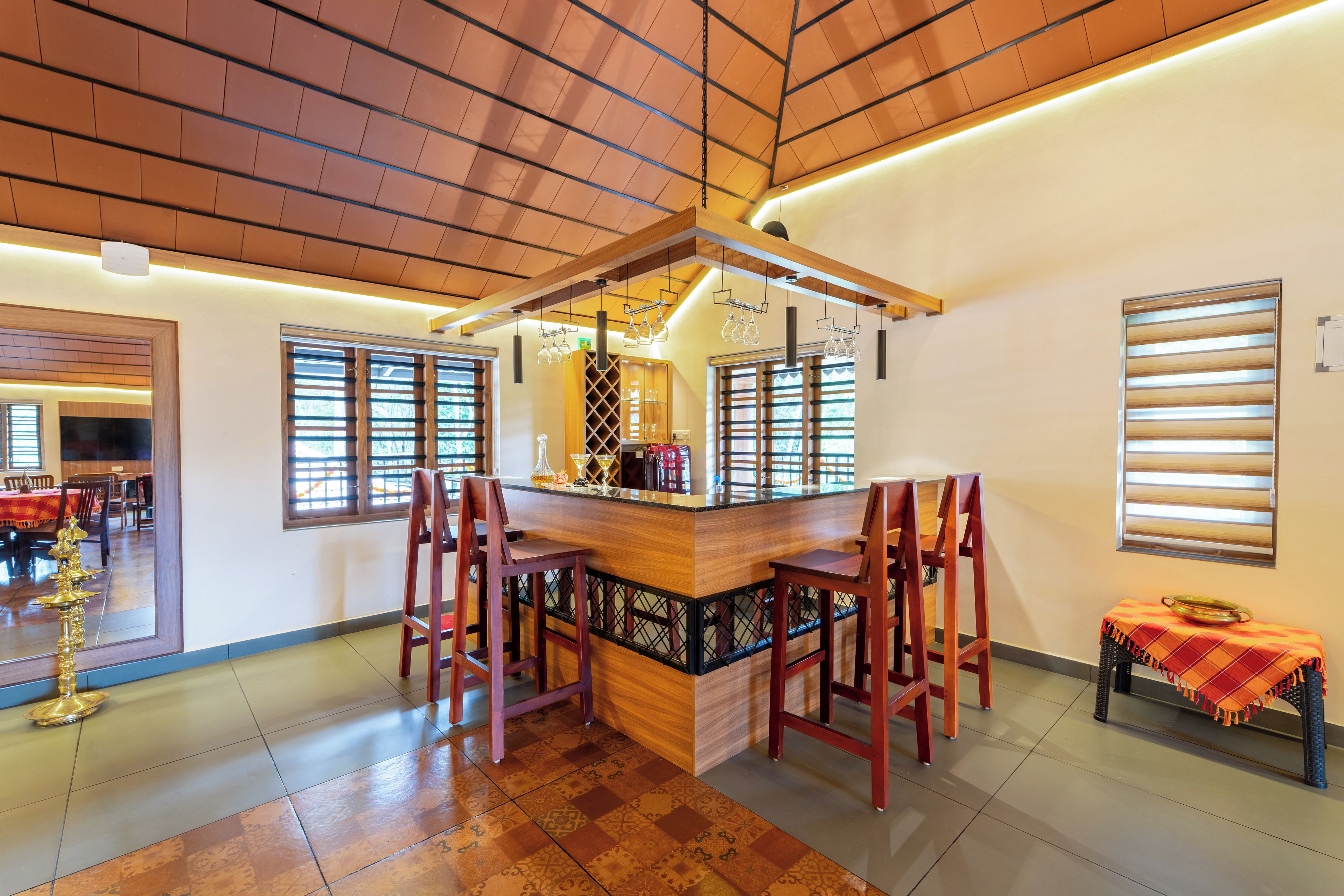 Zona de bar con mostrador de madera, varios taburetes y una estantería para vinos.