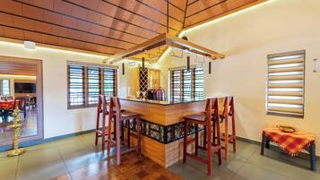 Zona de bar con mostrador de madera, varios taburetes y una estantería para vinos.