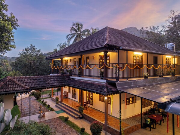 A two-story building with a balcony, solar panels, and a garden area.