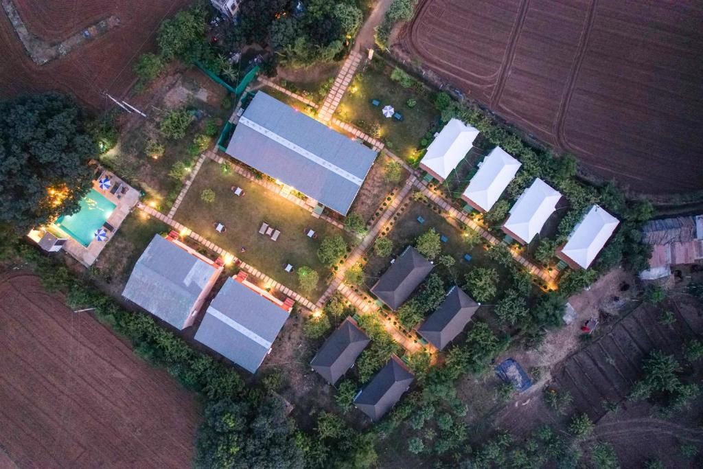 Luchtbeeld van een woongebied met meerdere huizen, een zwembad en een verlicht pad.