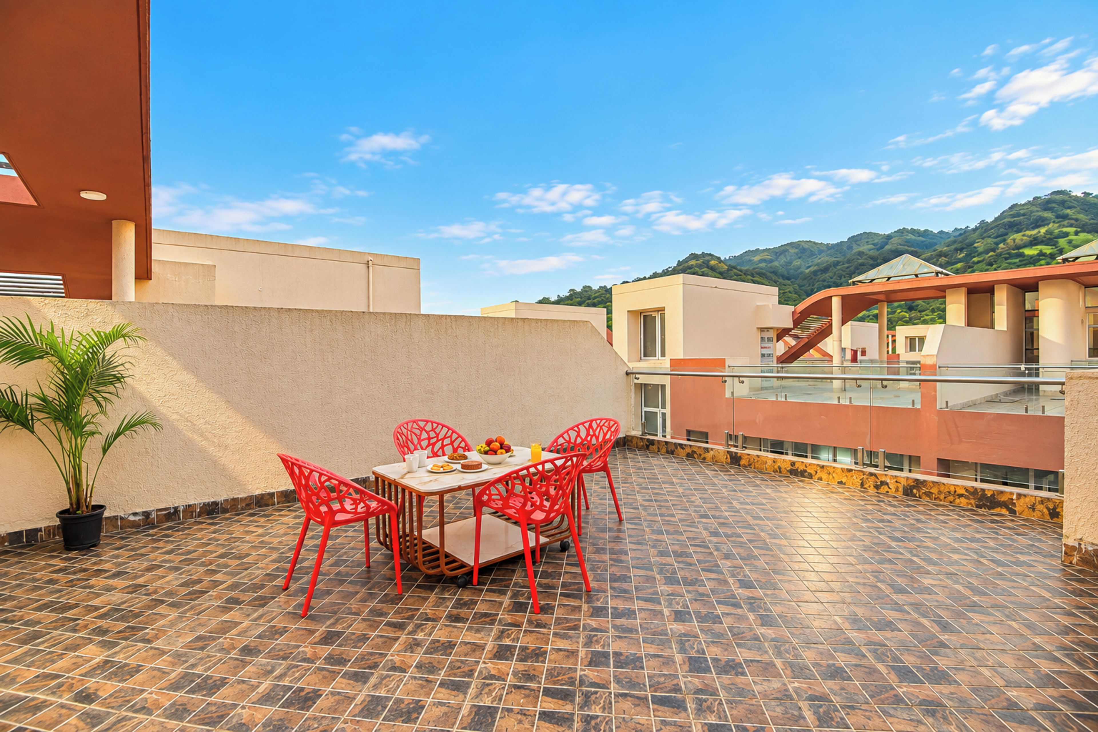 A terrace with a dining table, chairs, and a potted plant.