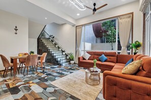 Una sala de estar moderna con una escalera, zona de comedor y un sofá con vistas al exterior.