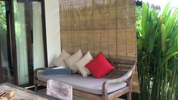 A room with a wooden sofa, a small table, and a bamboo screen.
