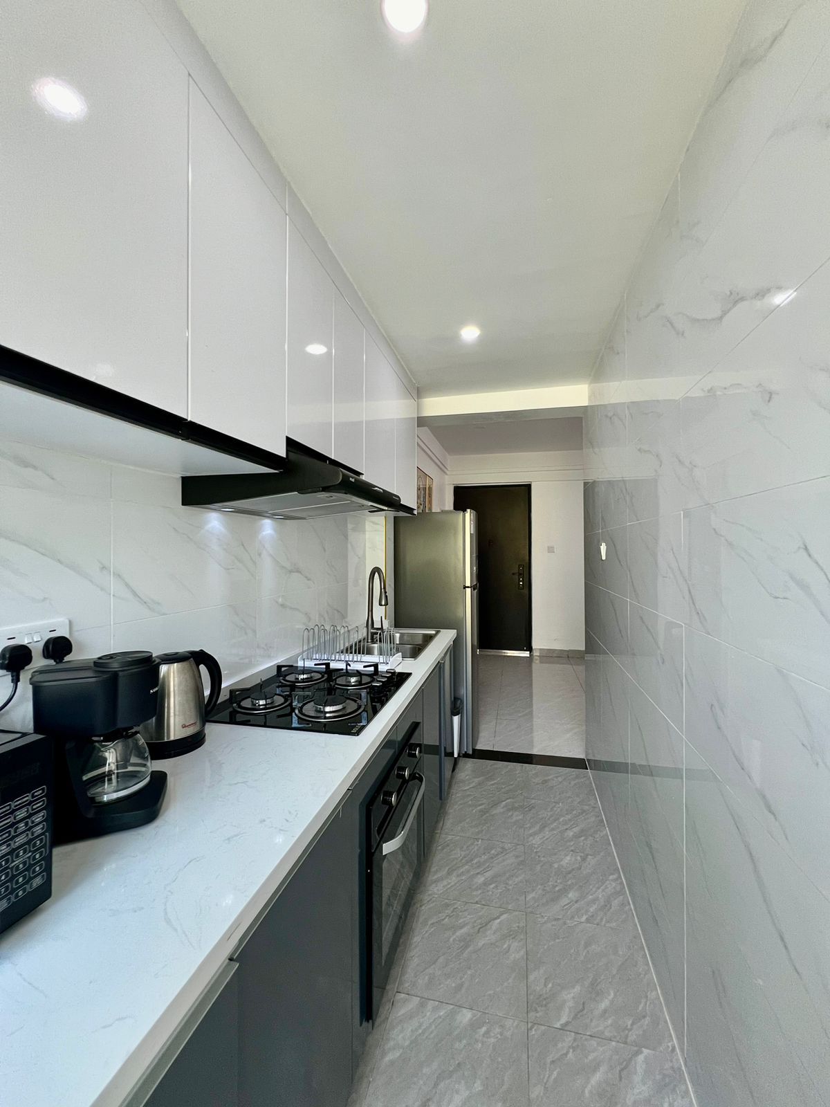 A modern kitchen with a gas stove, coffee maker, and stainless steel appliances.