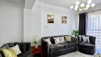 A modern living room with a sectional sofa, a small wooden side table, and a decorative plant.