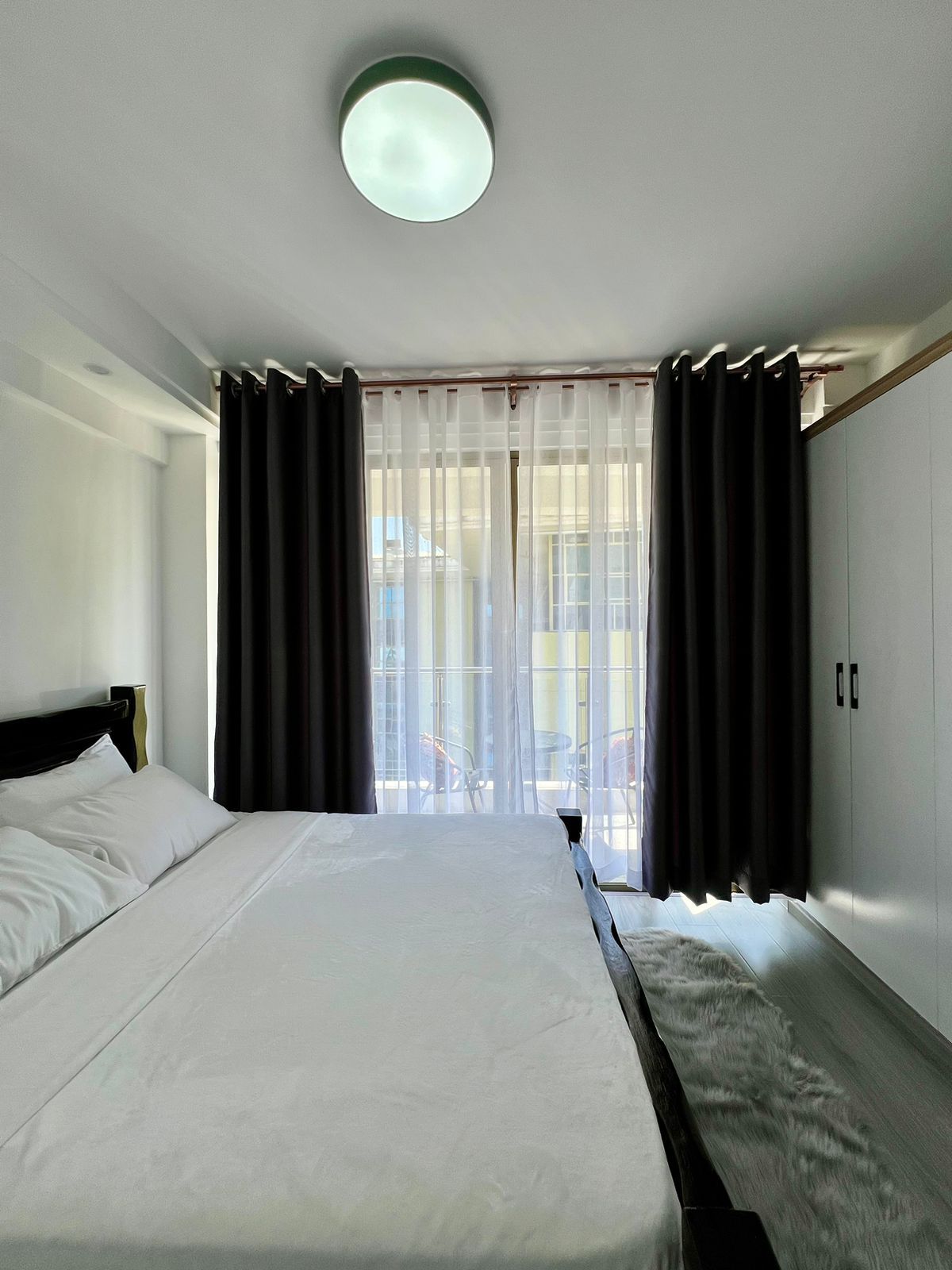 Une chambre d’hôtel avec un lit, des rideaux, une armoire et une vue sur l’extérieur.