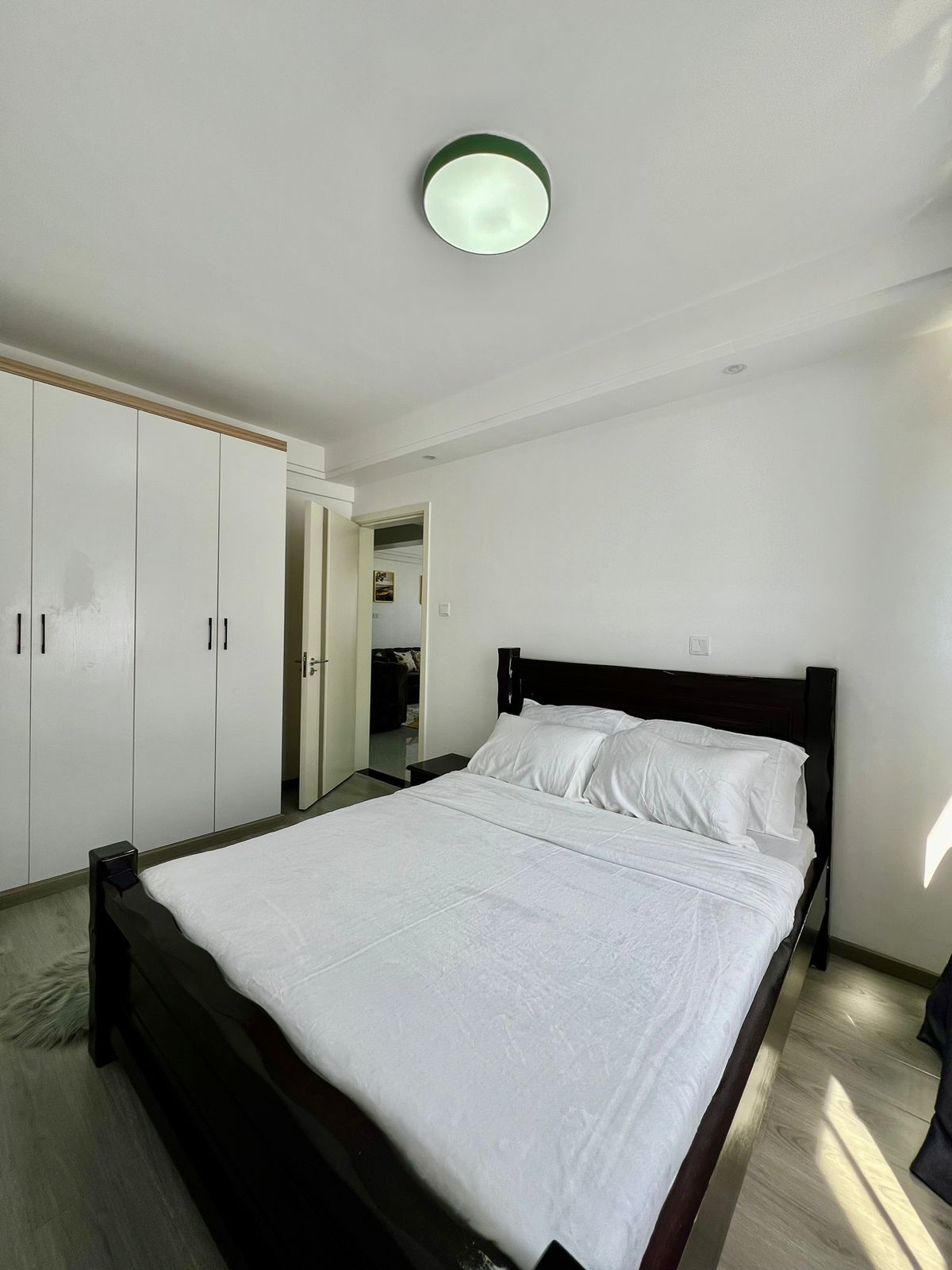 A bedroom with a bed, wardrobe, and a door leading to another room.
