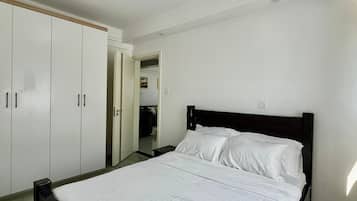 A bedroom with a bed, wardrobe, and a door leading to another room.