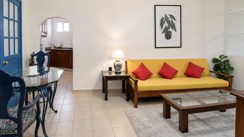A living room with a sofa, a coffee table, and a dining area with chairs and a table.