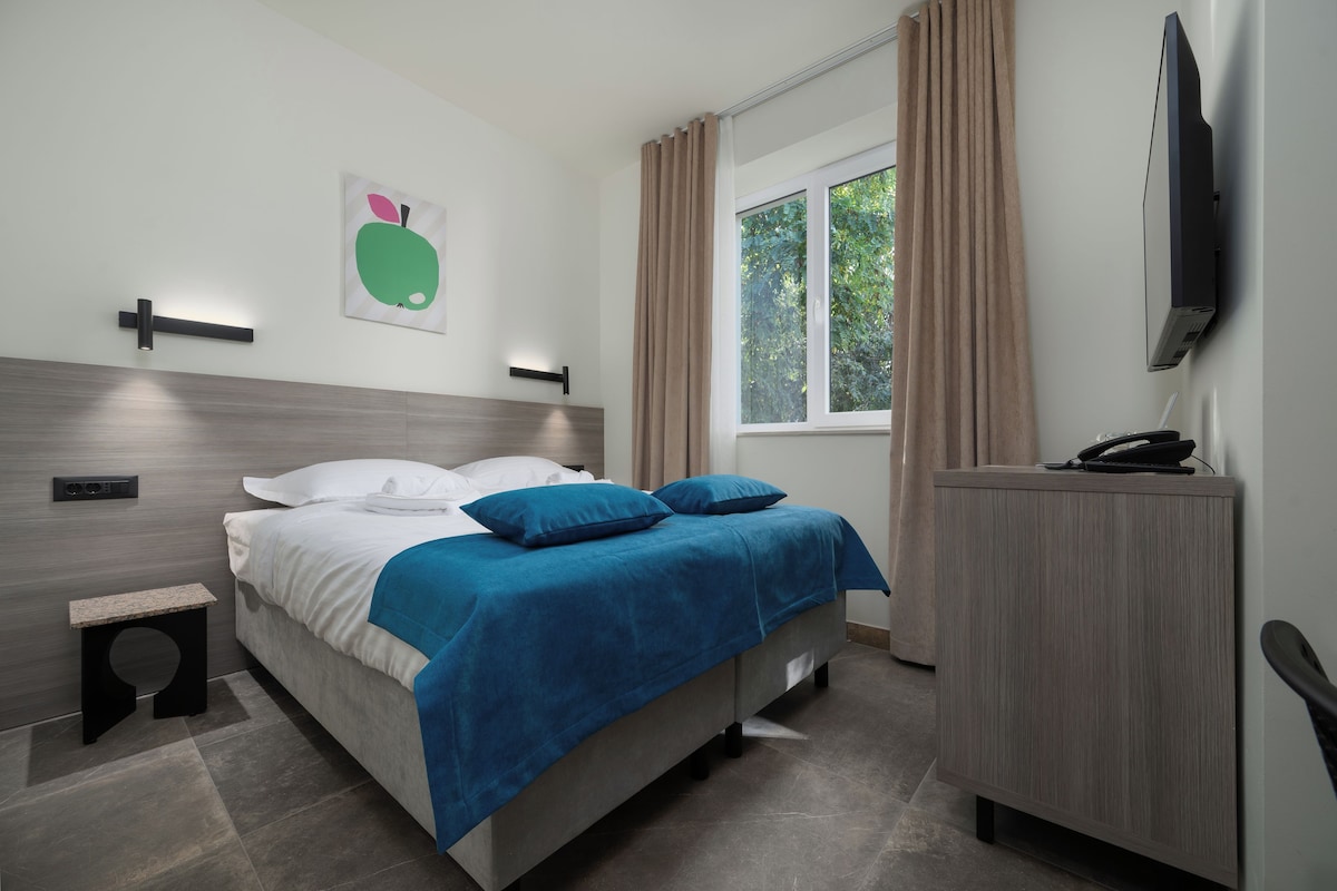 Habitación de hotel moderna con cama, escritorio, televisión de pantalla plana y ventana con cortinas.