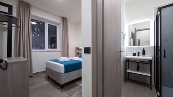 A hotel room with a bed, a desk, a telephone, and a window with curtains.